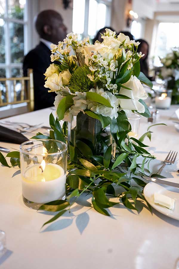 Tablescape Details | Photo by Still Shots Photography The tables were decorated with white flowers, greenery, and candles.
