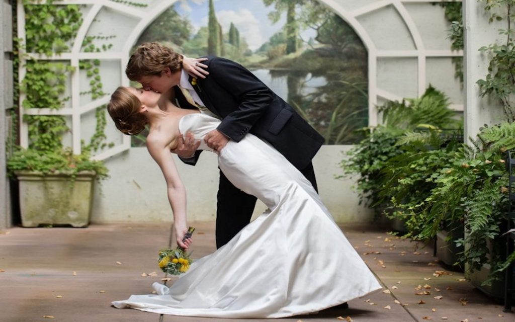O.Henry Hotel Weddings - Leah and Joe The bride and groom share a kiss in the English-inspired walled garden at O.Henry Hotel.